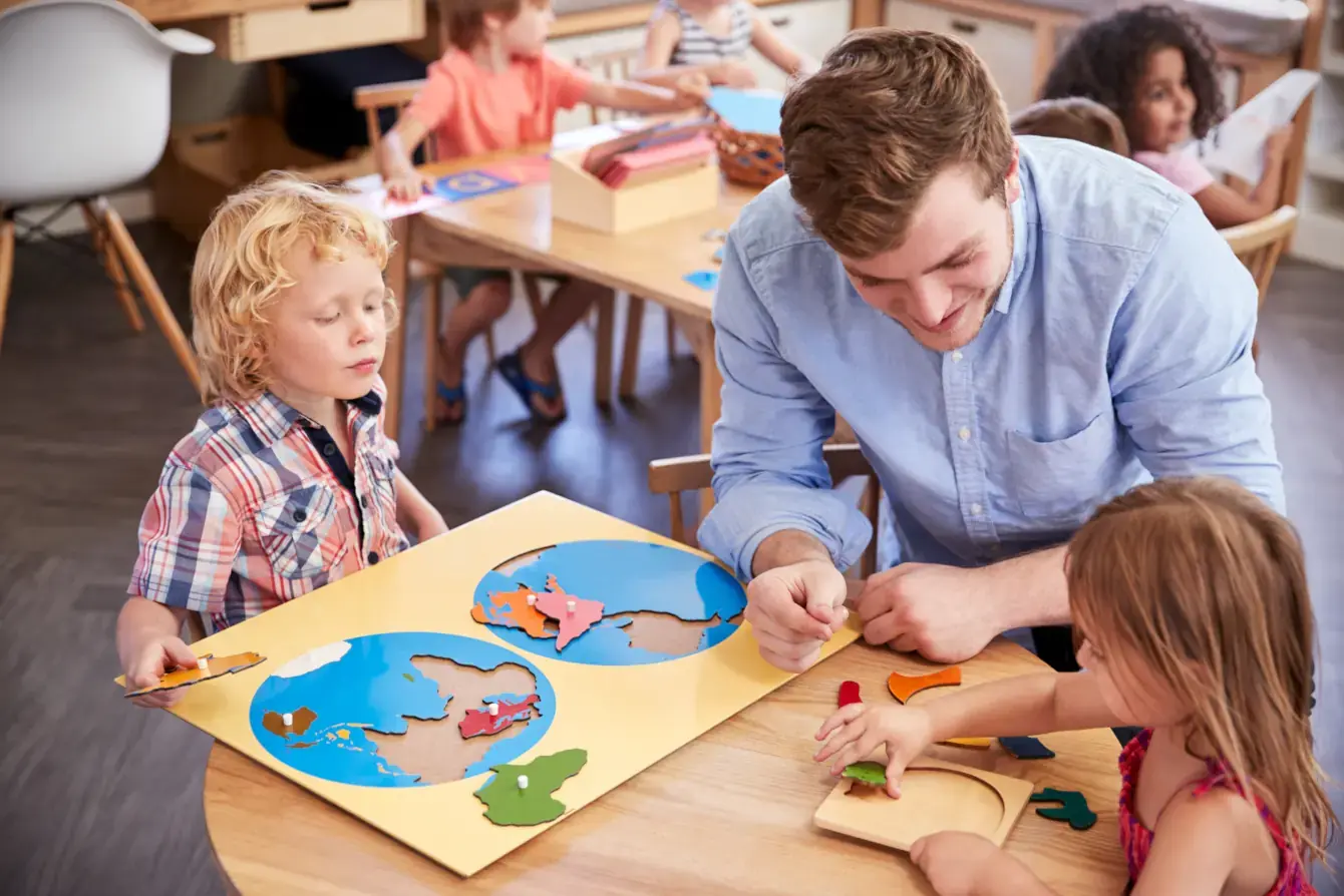 A Montessori teacher assisting preschool children in a Montessori classroom
